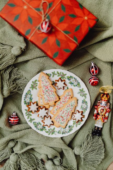 Overhead view of decorated Christmas cookies and festive ornaments on a plate.