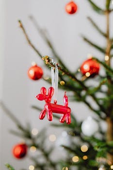 Close-up of a Christmas tree branch with colorful ornaments including a balloon dog decoration.