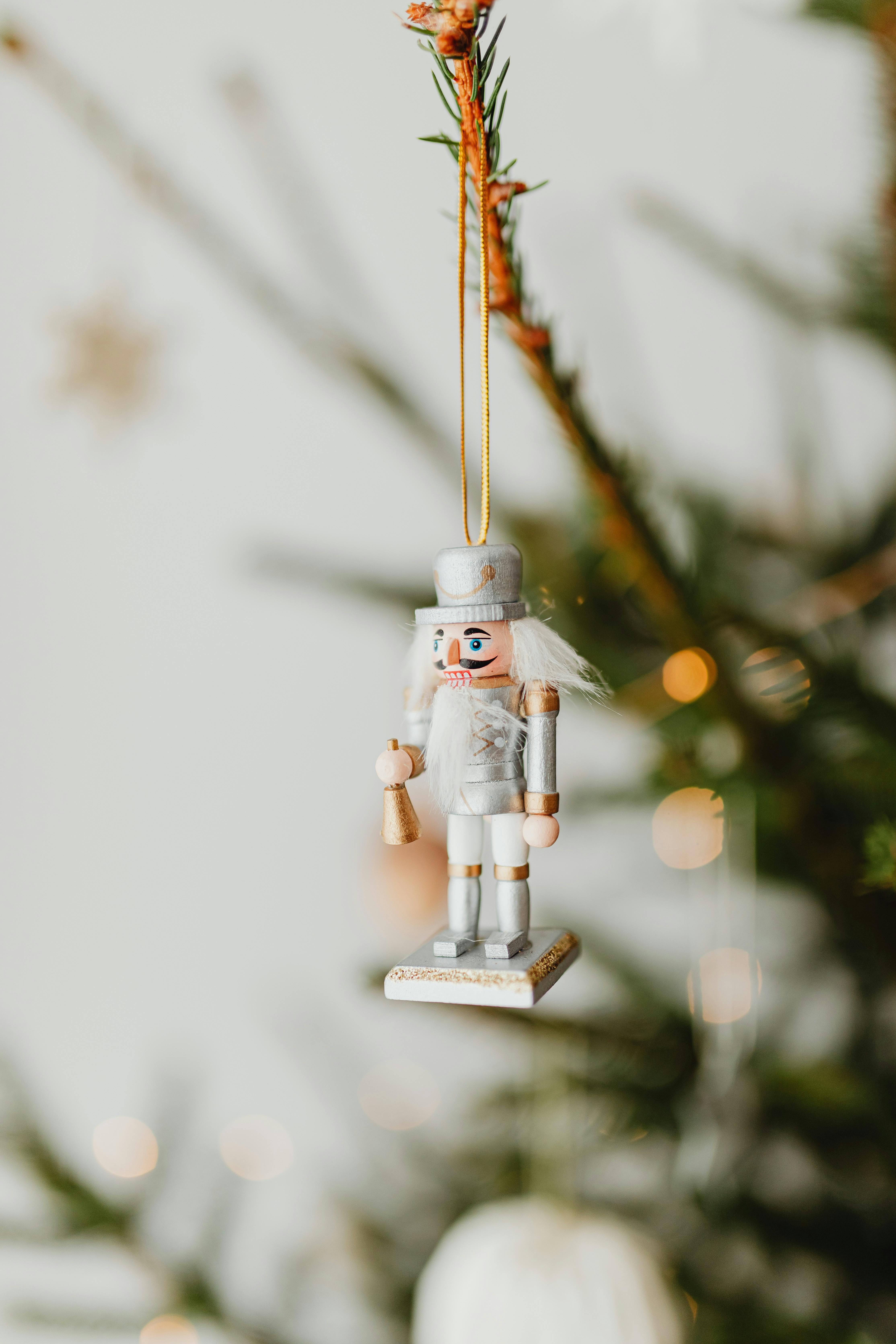 A close-up of a nutcracker ornament hanging on a Christmas tree with a blurred background for festive decor.