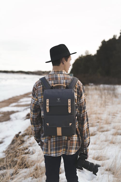 Unrecognizable photographer with backpack standing in field in winter