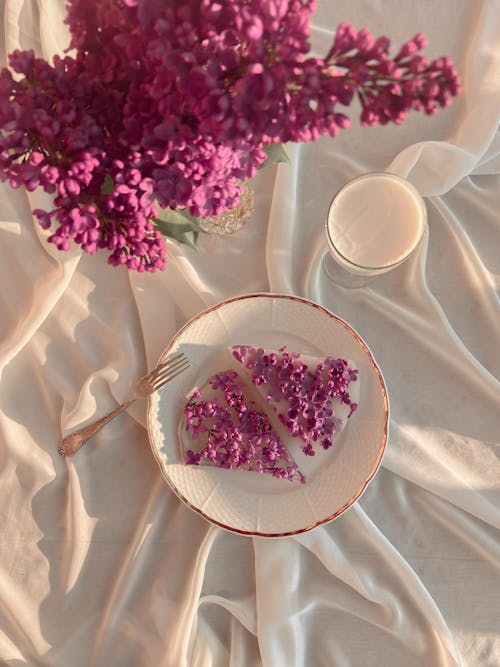 Top view of fresh blooming lilac flowers placed near petals in ice with glass of milk