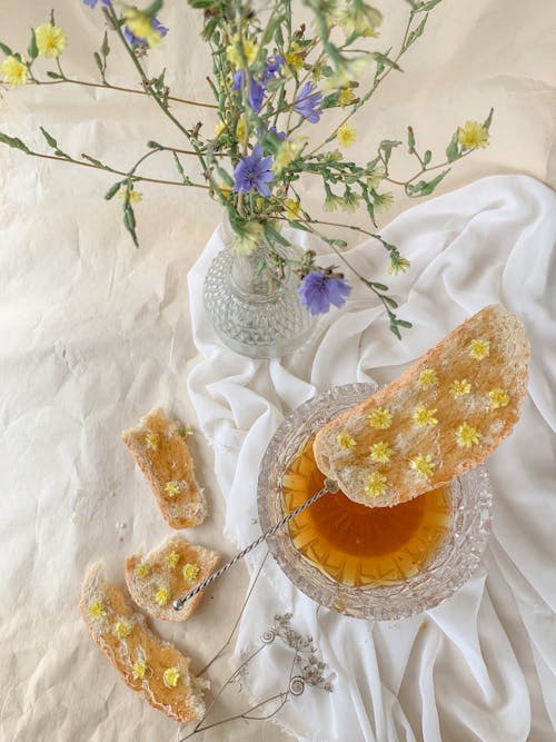 Bread with honey near vase of flowers