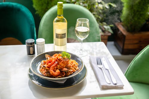 Free Close-Up Shot of a Dish on a Plate beside a Bottle of Wine Stock Photo