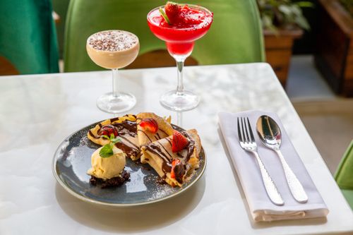 Free Elegant table setting with crepes, cocktails, and cutlery, perfect for a sweet indulgence. Stock Photo