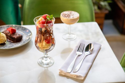 Free Close-up of a sundae with strawberries, chocolate syrup, and brownies on a table setting. Stock Photo