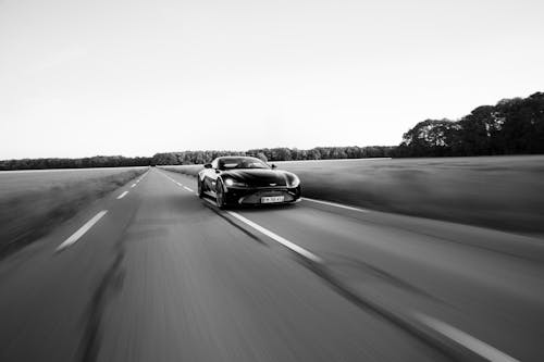 Grayscale Photo of a Sports Car on the Road