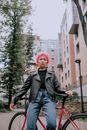 一位粉色头发的时尚女性在城市中自信地骑着自行车摆姿势