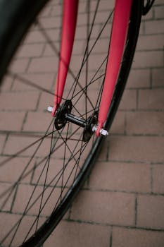 Detail shot of a red bicycle wheel with spokes on a brick pavement.