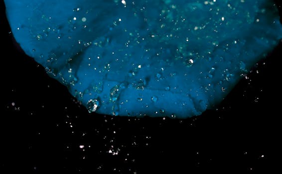 这张高分辨率微距照片捕捉了蓝色表面上的水滴，形成了一幅抽象图案