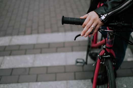 城市街道上，一位时尚女子抓着粉色自行车的车把