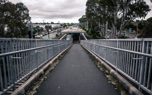 Free A concrete pathway with metal railings leads to a train station under cloudy skies. Stock Photo