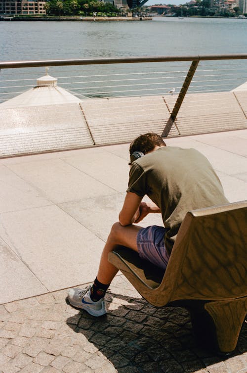 Young man sitting and resting on seat on embankment