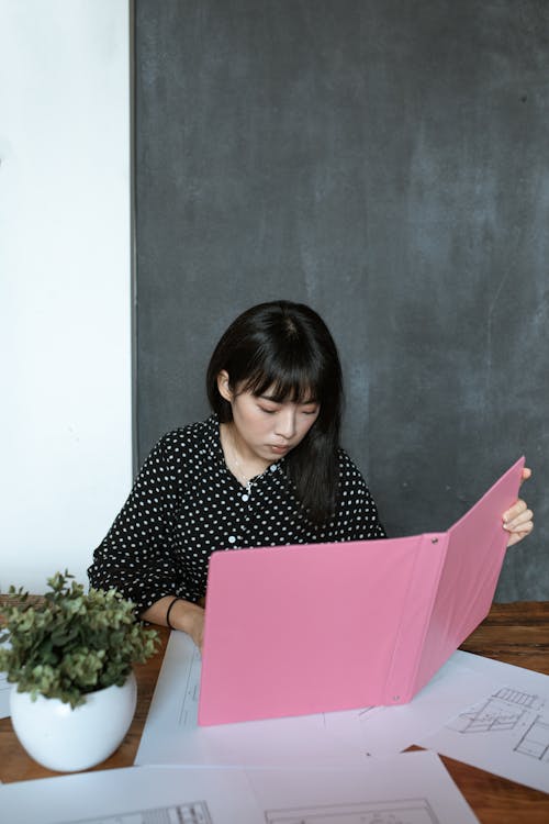 Donna In Camicia A Maniche Lunghe A Pois Bianco E Nero Che Tiene Cartella Rosa