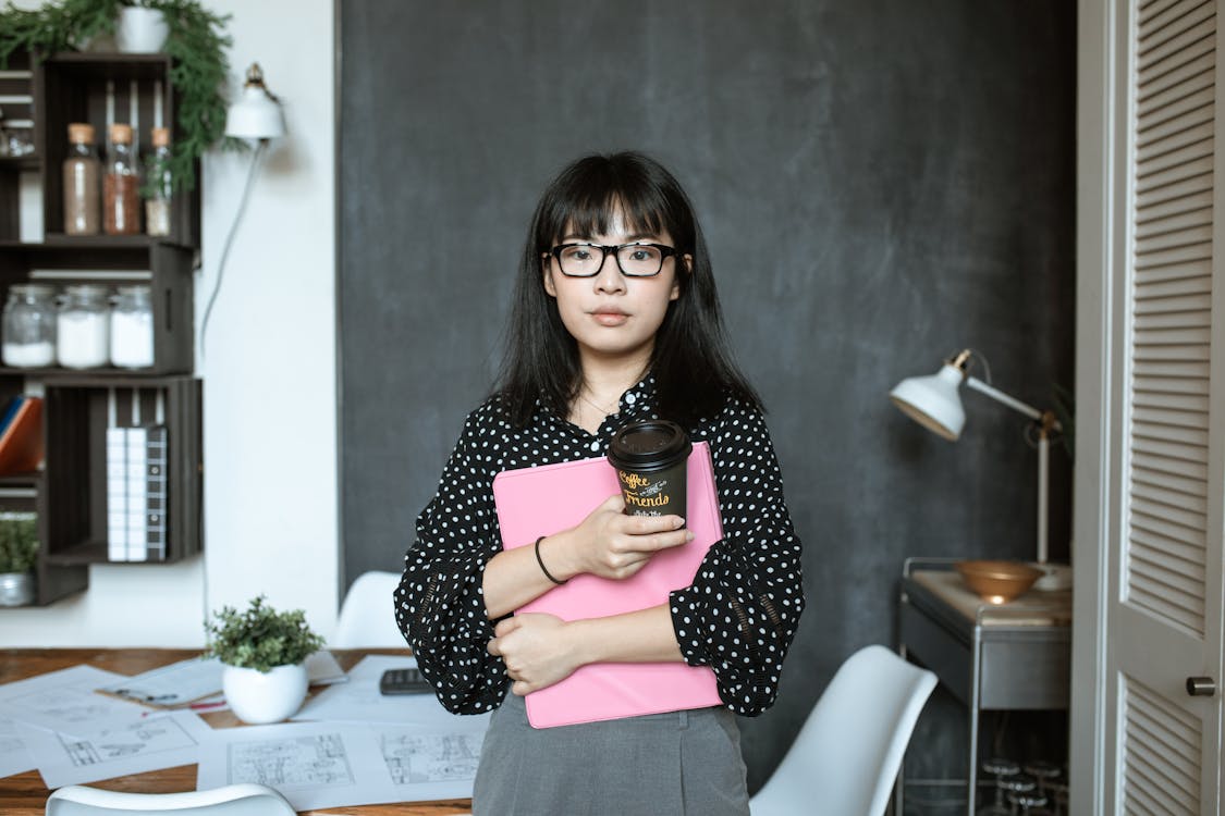 Free A Woman Holding a Pink Folder and a Coffee Cup Stock Photo