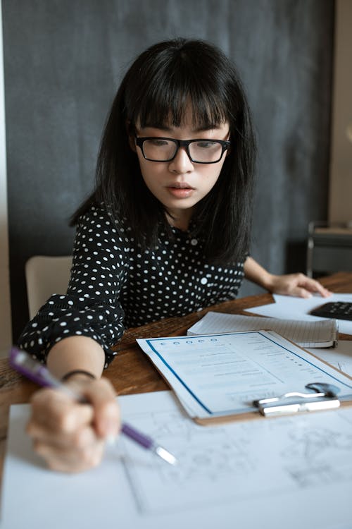 黑色和白色的圓點長袖襯衫，戴著黑色鏡框眼鏡的女人