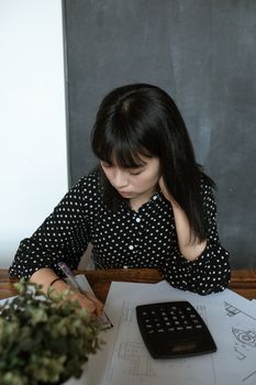 在室内工作区，亚洲妇女专注于文件和计算器相关工作