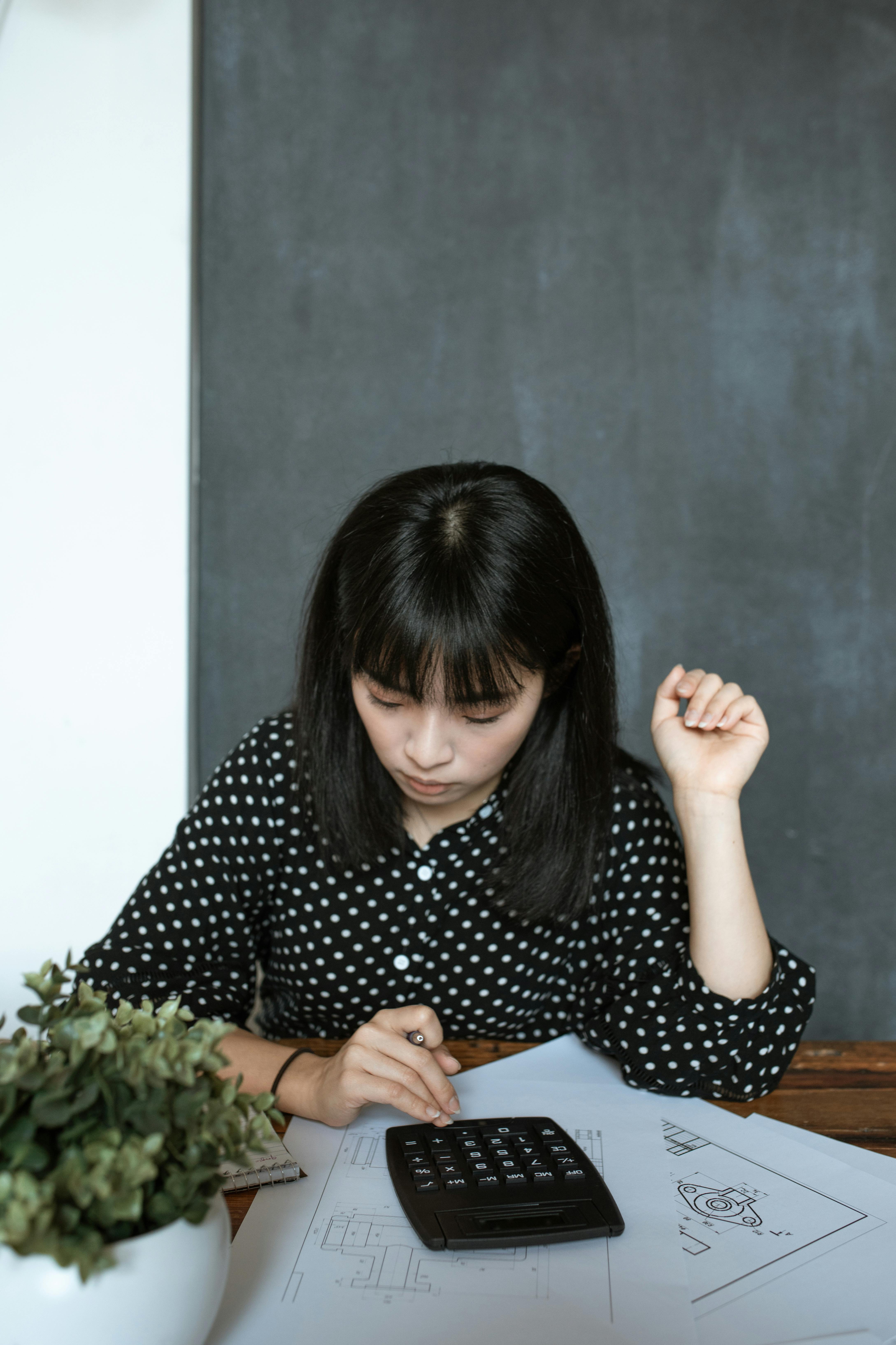 a woman wearing a polka dot blouse using a calculator