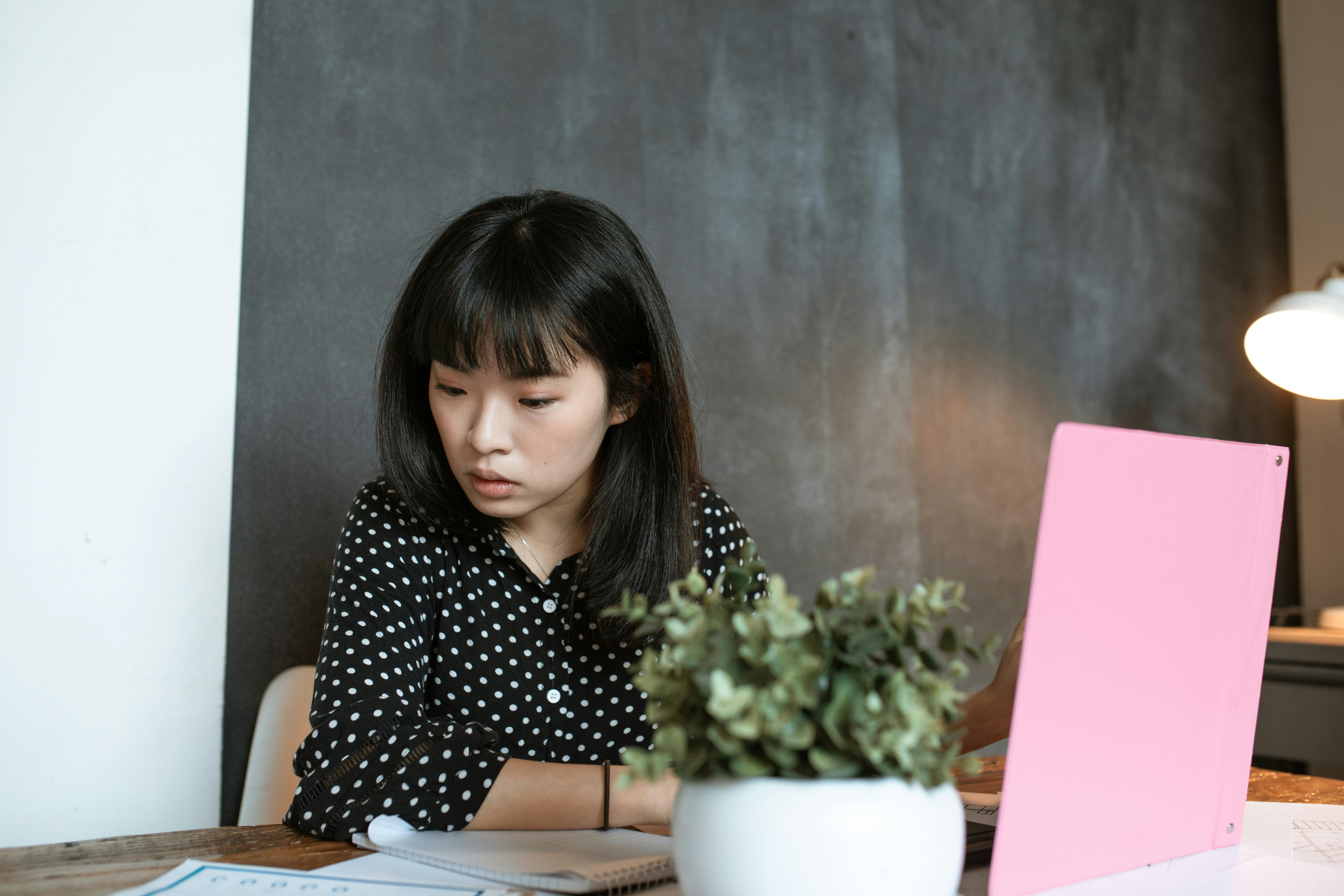 a woman wearing a polka dot blouse reading a document