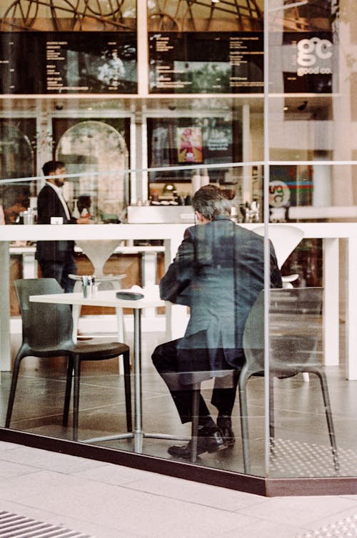 Back view of anonymous mature male in elegant suit having dinner in comfortable modern restaurant