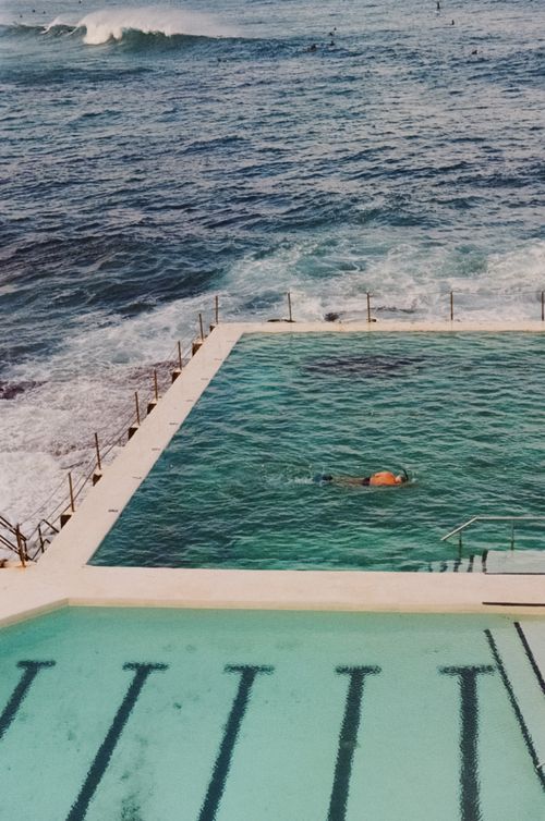Free A swimmer in an oceanfront pool with waves crashing nearby, offering a scenic coastal experience. Stock Photo