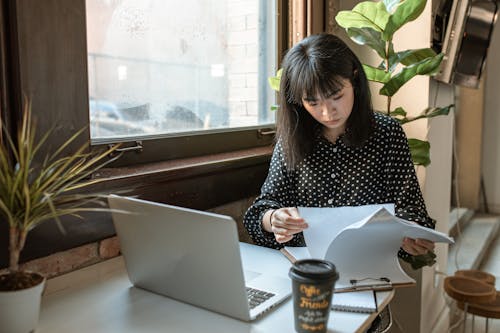 Woman in Black and White Long Sleeve Shirt Looking On A Paperwork