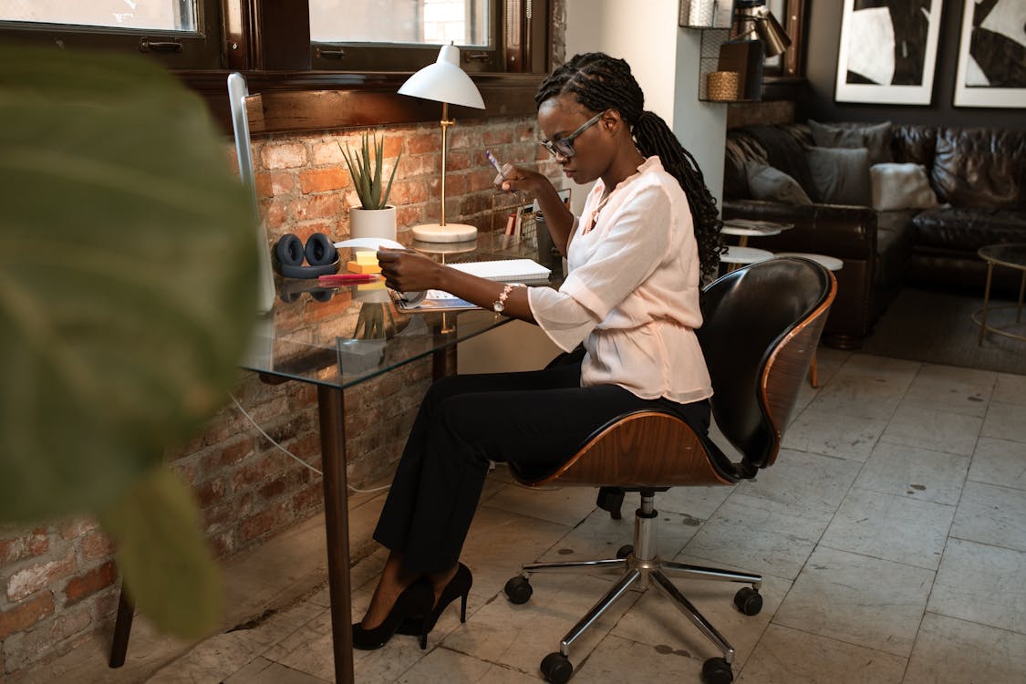 Free Businesswoman Sitting on Black Leather Chair Looking Over Some Paperwork Stock Photo
