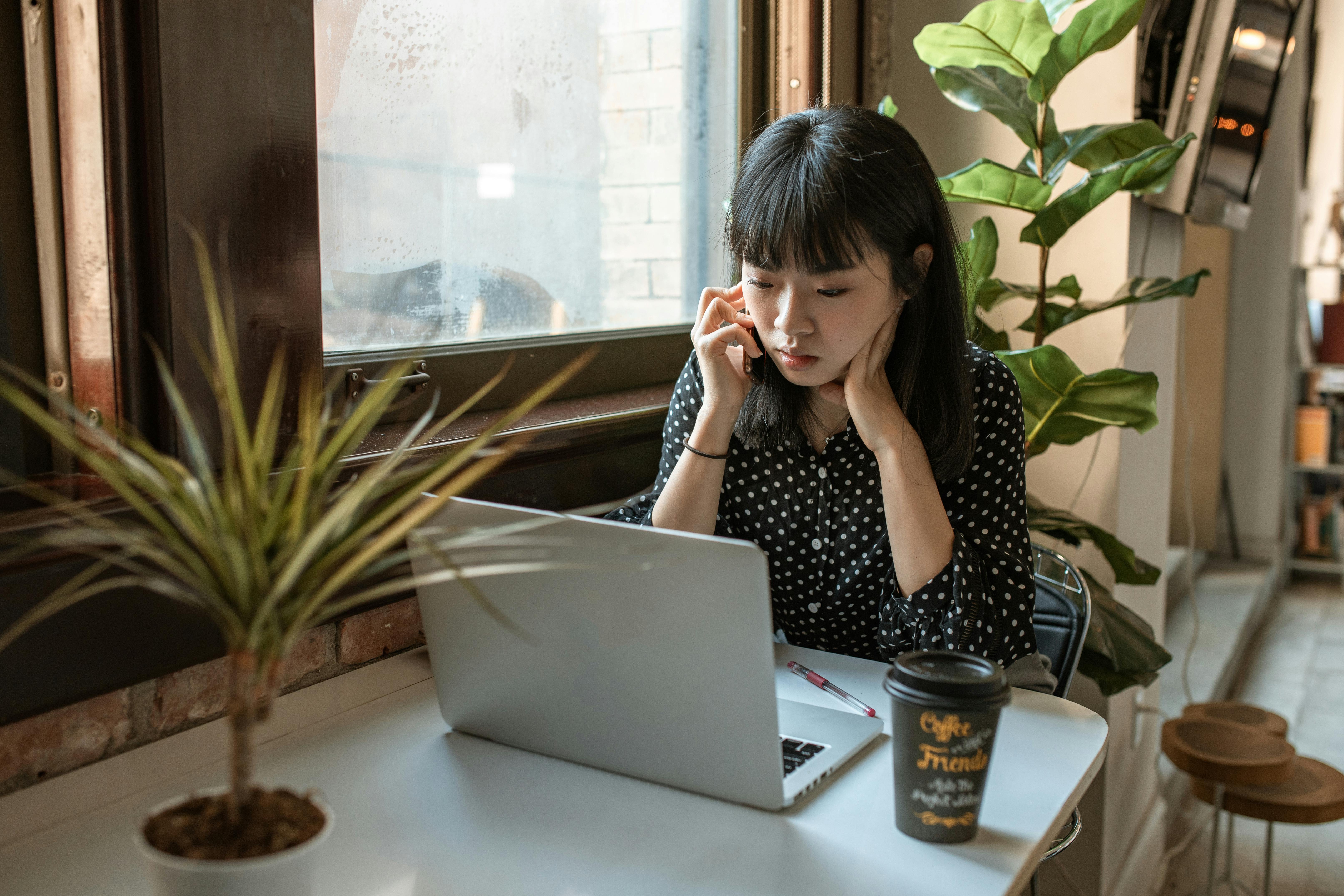 woman in black and white long sleeve shirt sitting at table with macbook