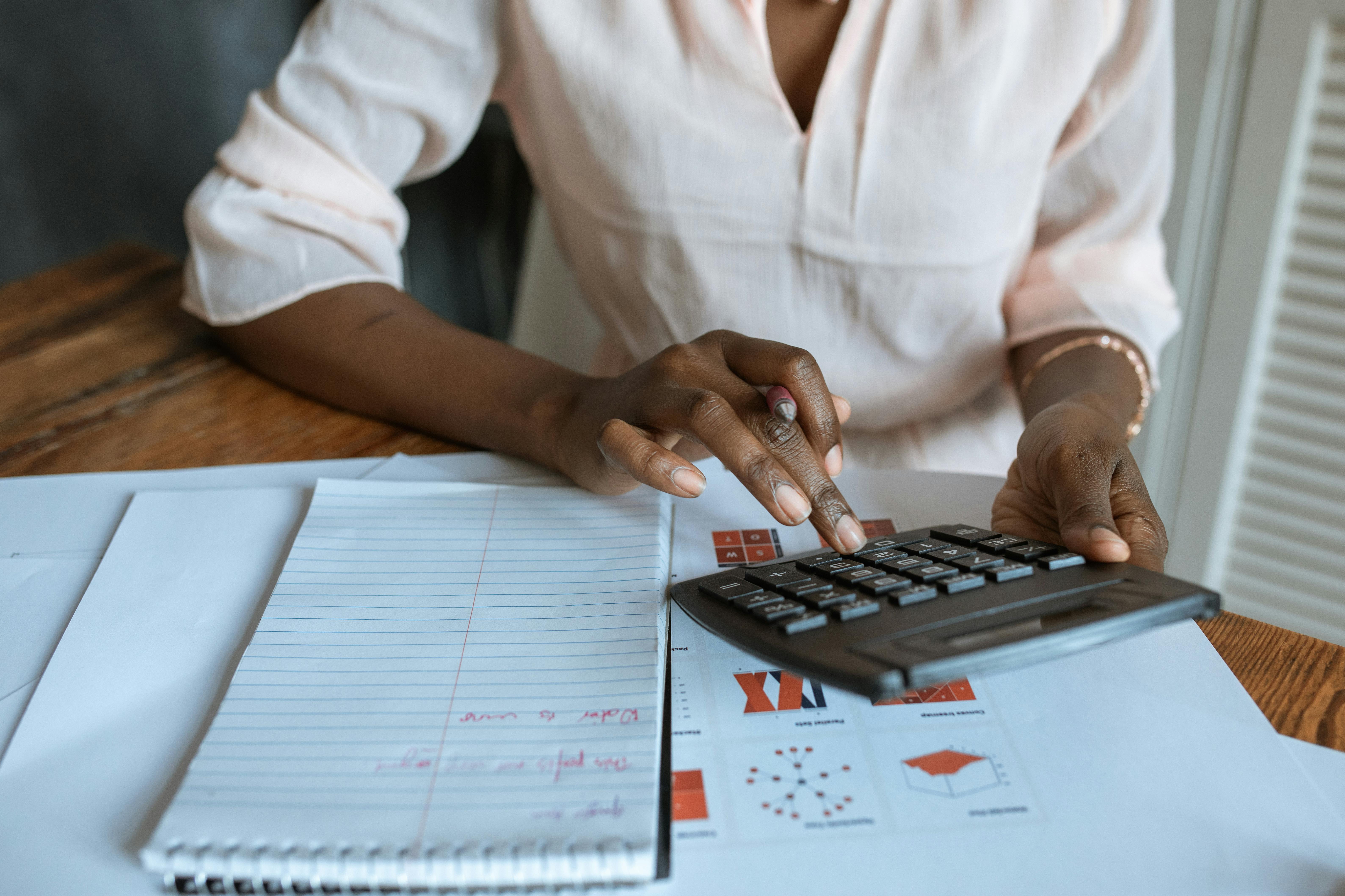 person in white dress shirt using a calculator