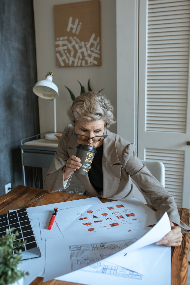 A Woman Drinking Coffee While Looking At The Document