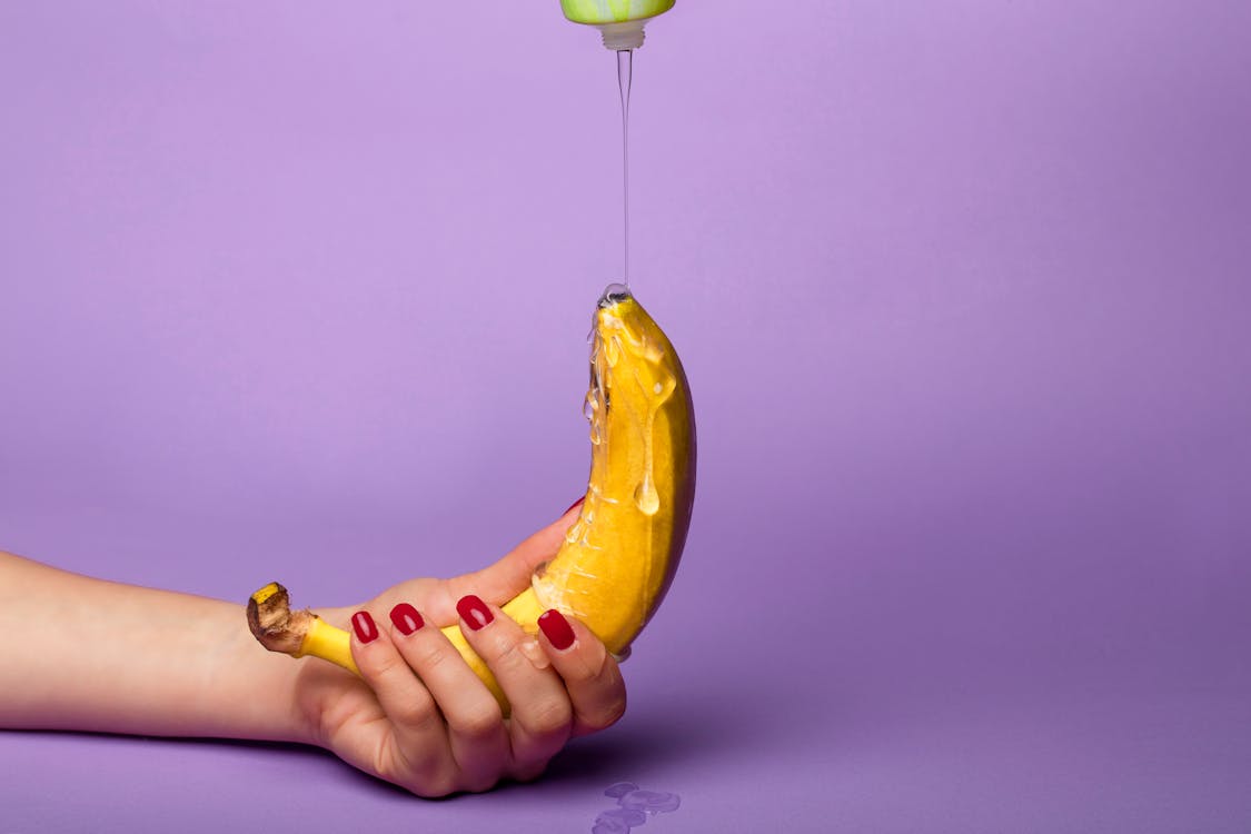 Free Person Holding Yellow Banana With Syrup Stock Photo