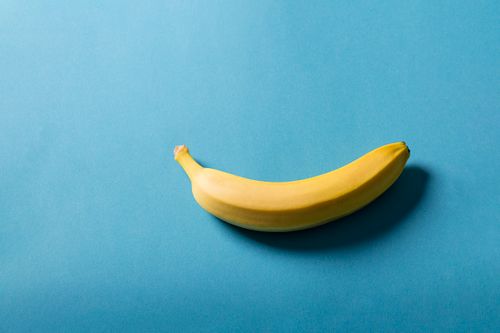 Free A fresh banana placed on a vibrant blue surface, showcasing minimalistic style. Stock Photo