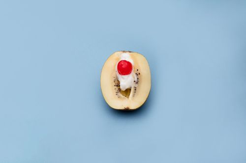 Free Artistic presentation of a kiwi with cream and cherry on a blue background. Stock Photo