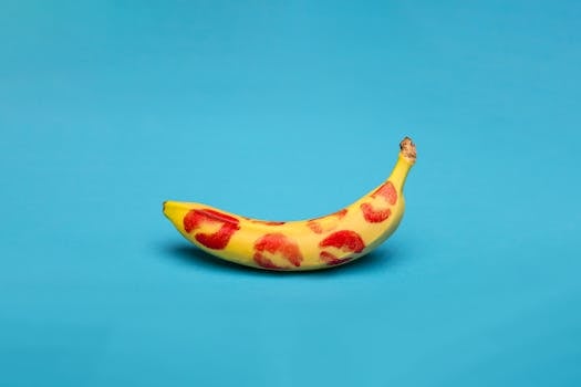 A vibrant studio shot of a banana covered in red lipstick kiss marks against a blue background.