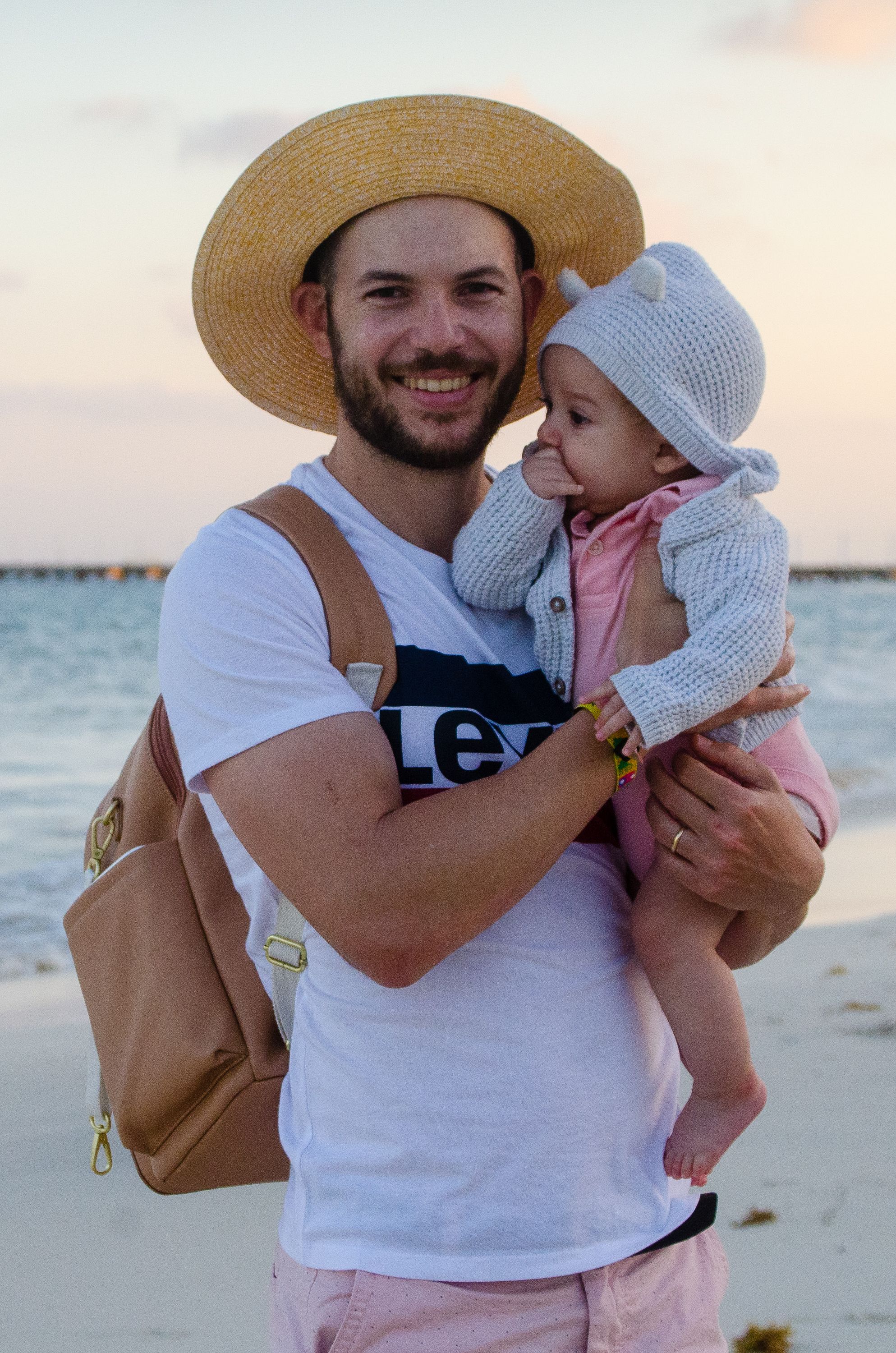 A father and baby enjoying a serene moment on a beach at sunset, capturing family joy.