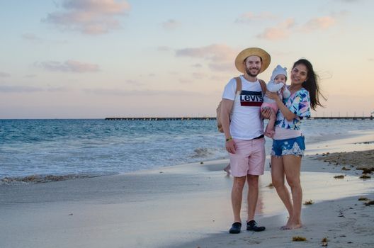 Smiling family enjoying beach vacation during beautiful sunset by the ocean.