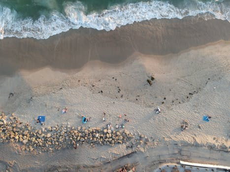 Drone shot of people relaxing on Huntington Beach, California's sandy coast.