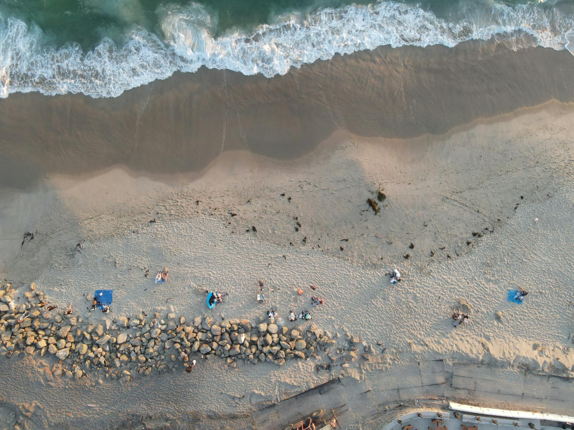 Drone shot of people relaxing on Huntington Beach, California's sandy coast.