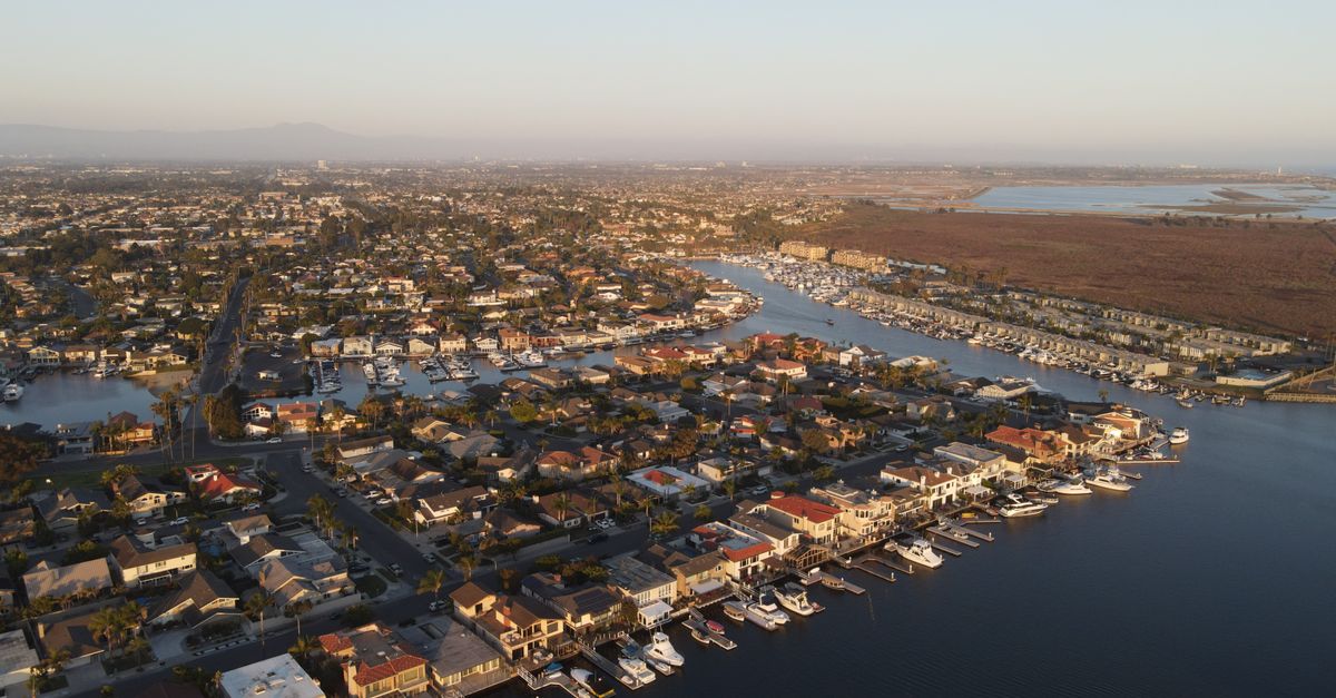Stunning aerial view of Huntington Beach harbor showcasing boats and residential area at sunset.