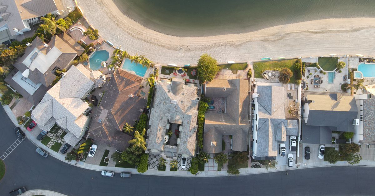 Aerial shot of residential homes along the beach in Huntington Beach, CA, capturing rooftops and coastal scenery.