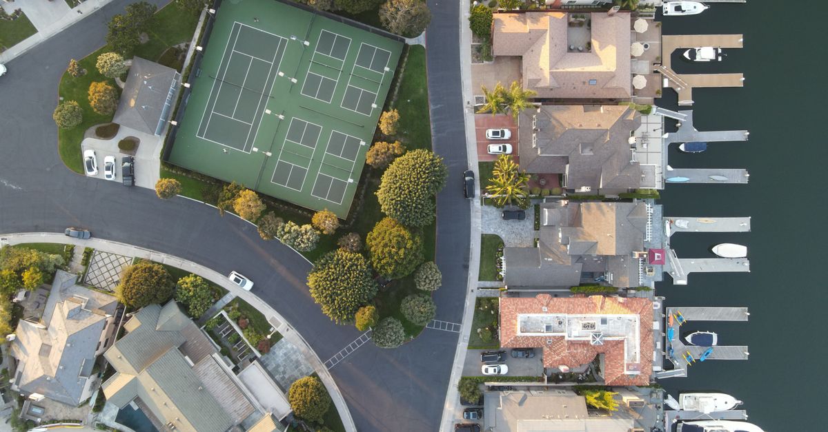 Aerial drone shot showing a marina in Huntington Beach with tennis courts and nearby houses.