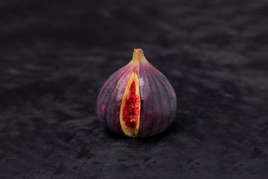 在黑暗背景下，一个成熟的无花果果实被切片，露出其充满活力的内部特写