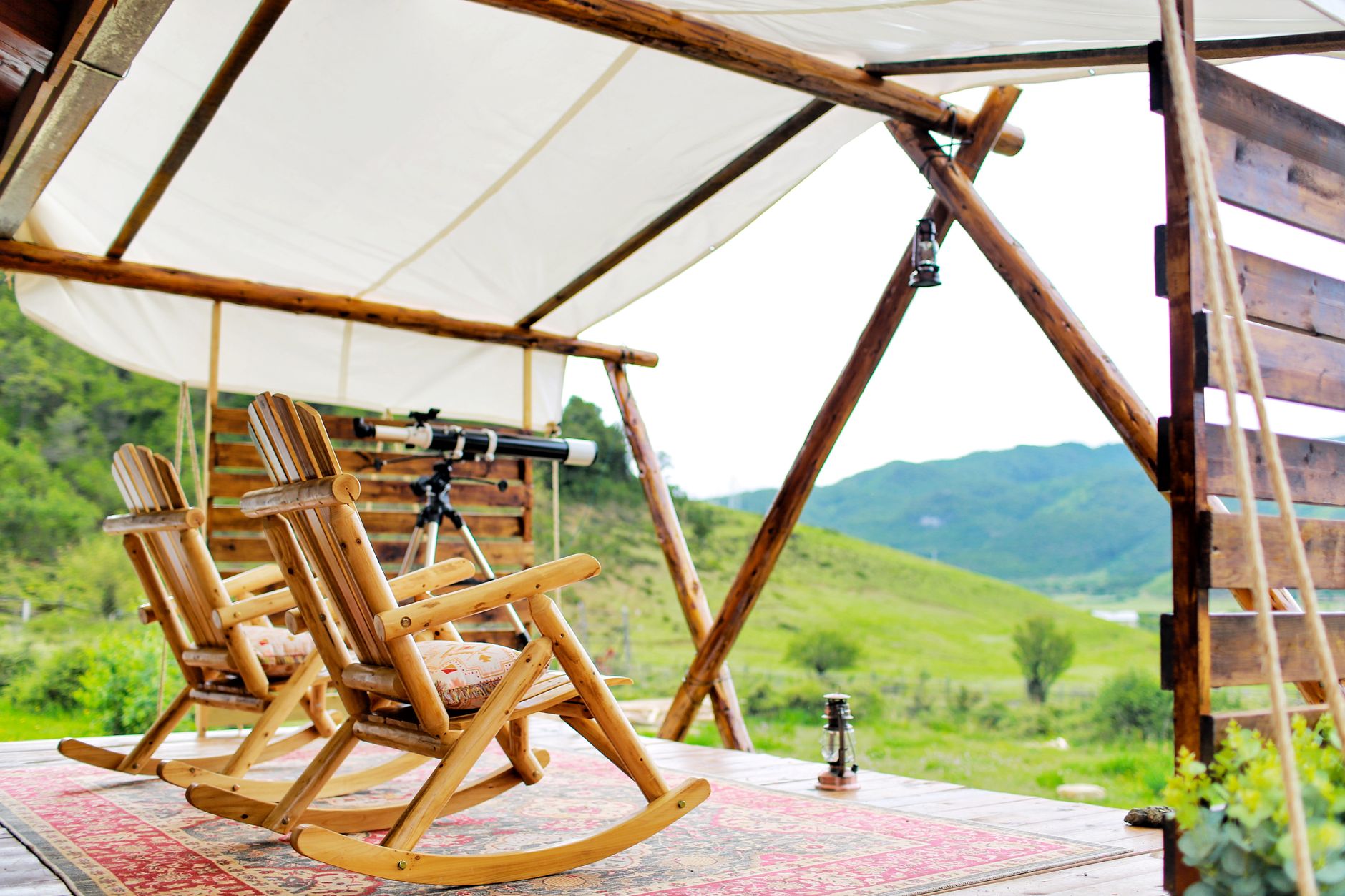 Peaceful wooden deck in Yunnan, China with rocking chairs and a telescope offering scenic mountain views.
