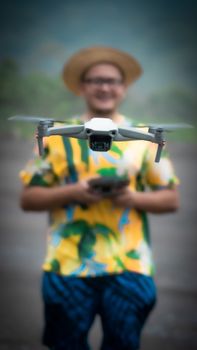 Close-up shot of a drone in flight with a blurred operator holding a controller in the background.
