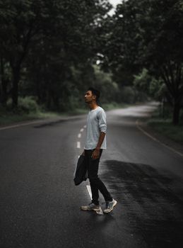 一名年轻人背着背包站在印度的一条森林道路上