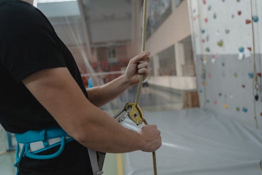 Close-up of a person holding a climbing rope, highlighting safety equipment used in indoor rock climbing.