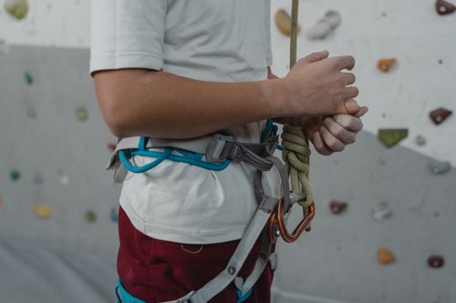 Free A young rock climber secures his harness and rope in an indoor climbing gym. Stock Photo