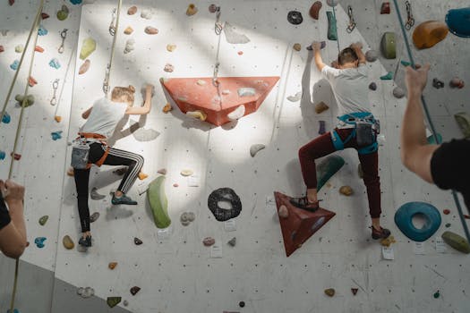 Two young climbers ascend an indoor rock wall, focused and determined.
