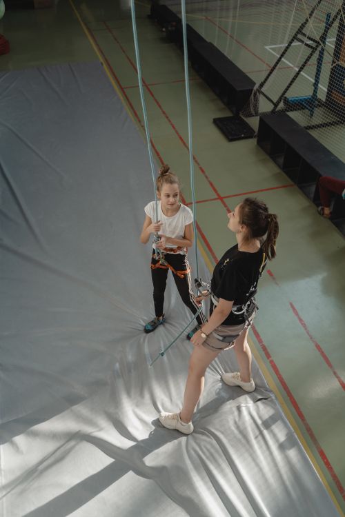 Free A young girl receives an indoor climbing lesson from an adult instructor using ropes and harnesses. Stock Photo