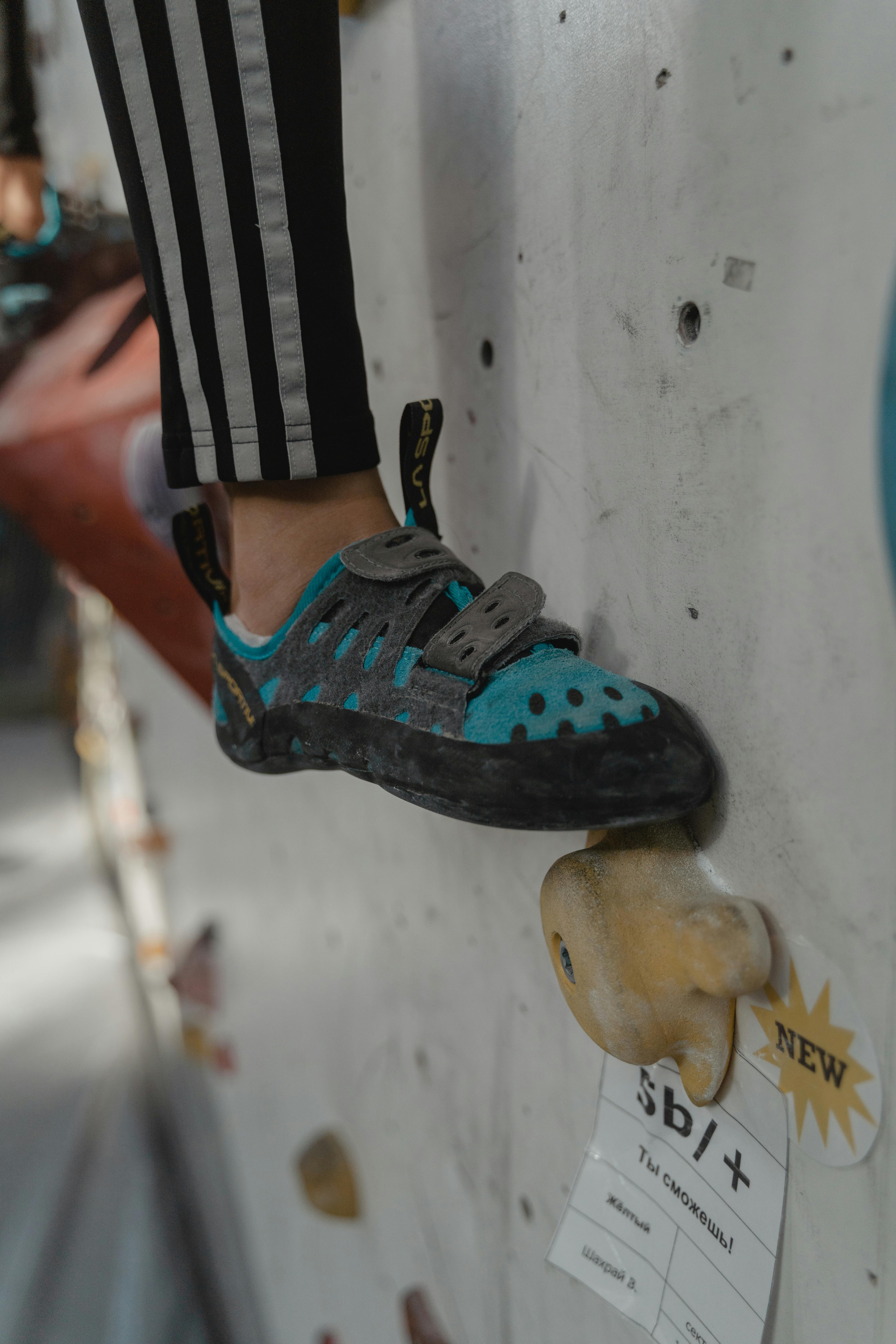 Detailed shot of a climber's shoe gripping a hold on an indoor climbing wall, showcasing precision and technique.