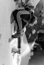 Grayscale Photo of a Person Wall Climbing